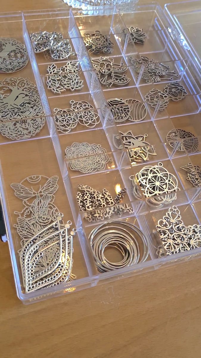 Bakje vol zilverkleurige metalen bedeltjes om uit te kiezen tijdens de workshop