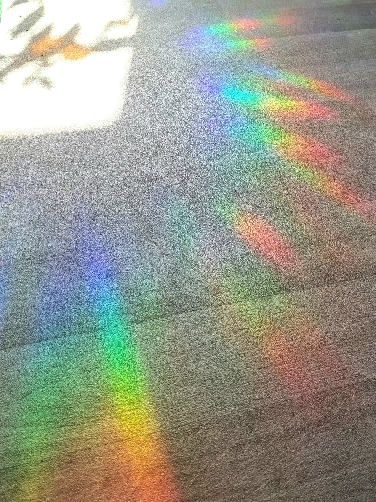 Regenboog van een kristallen suncatcher over vloer en muur