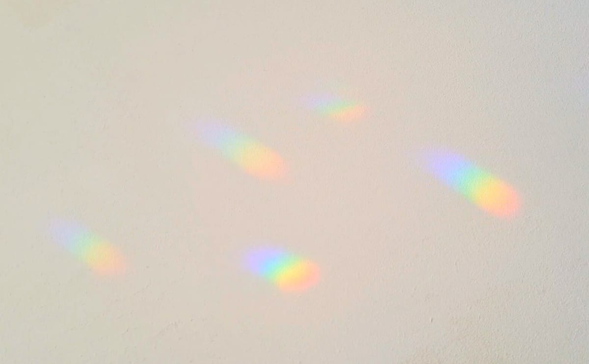 Kleine regenboogjes van een suncatcher op een lichte muur
