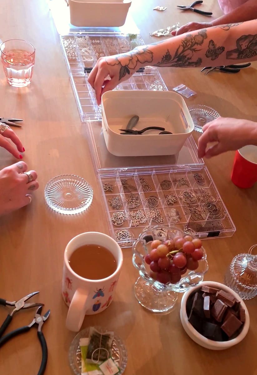 Een groep maakt samen kristallen suncatchers aan een gezellige werktafel vol kralen en bedeltjes